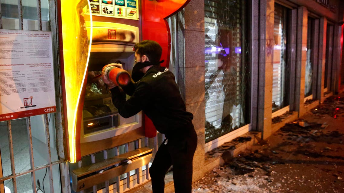An anti-government protester destroys an ATM machine during ongoing protests against the Lebanese central bank's governor on Jan. 14, 2020 in Beirut. (AP)