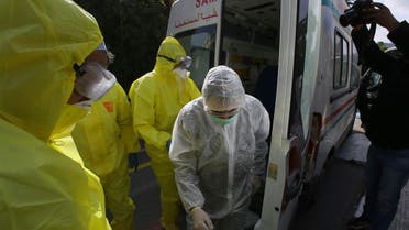 Medics stand outside a clinic where passengers and the crew of a flight went in for coronavirus tests, in Algeria, on Wednesday, February 26, 2020. 