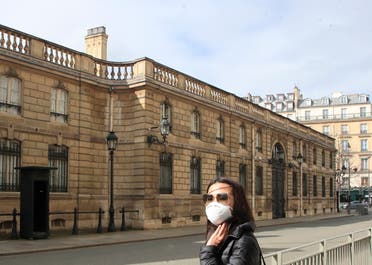 A woman wearing a mask as a precaution against the new coronavirus stands outside the Elysee Palace in Paris, on Wednesday, March 11, 2020. (AP) 