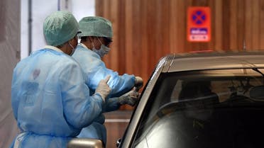 Medical staff take samples to a driver at a "drive-through" testing facility for the novel coronavirus at the "Hopital de la Citadelle" hospital in Liege, on it's opening day on March 10, 2020. (AFP)