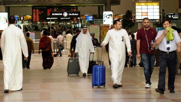 Passengers walk under the flight schedule board showing several cancelled flights, in Kuwait International Airport. (File photo: Reuters)