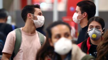Passengers, wearing protective face masks, wait for checking-in before boarding their flights to the U.S. at Madrid's Adolfo Suarez Barajas airport, Spain March 12, 2020. REUTERS/Sergio Perez