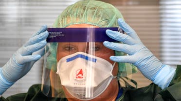 A nurse prepares her mask before she demonstrates a coronavirus test at the infection station of the university hospital in Essen, Germany, on March 12, 2020. (AP)