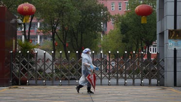 A resident in protective gear walks past the entrance of a closed secondary school in Wuhan, the epicentre of the novel coronavirus outbreak, Hubei province, China March 9, 2020. REUTERS