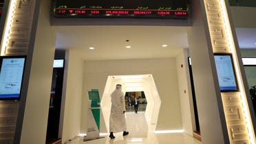 An Emirati trader passes under the stocks display screen at the Dubai Financial Market in Dubai, United Arab Emirates, Sunday, March 8, 2020. (AP)