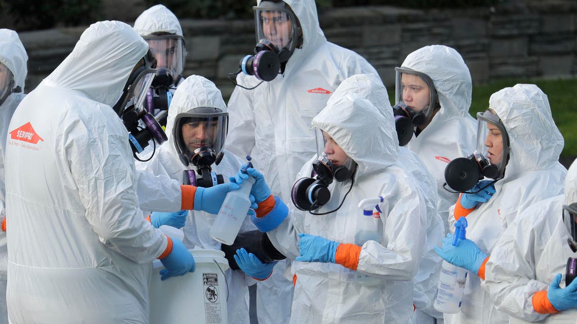 Workers from a Servpro disaster recovery team wearing protective suits and respirators are given supplies as they line up before entering the Life Care Center in Kirkland, Wash., to begin cleaning and disinfecting the facility on March 11, 2020. (AP)