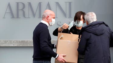 A worker holds a face mask outside the theatre where the Italian designer Giorgio Armani said his Milan Fashion Week show would take place to safeguard the health of press and buyers after a coronavirus outbreak in northern Italy, in Milan, Italy, February 23, 2020. REUTERS/Alessandro Garofalo