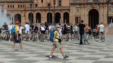 A tourist wearing a protective mask walks at Plaza de Espana in Seville on March 11, 2020 after Spain banned all air traffic from Italy, closed schools and blocked fans from football matches due to the coronavirus outbreak. (AFP)