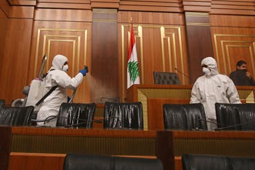 Sanitary workers disinfect the desks and chairs of the Lebanese Parliament in central Beirut on March 10, 2020 amid the spread of coronavirus in the country.  (AFP)