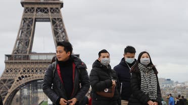 People walk near the Eiffel Tower wearing protective face masks amid the outbreak of COVID-19, the new coronavirus, on the Trocadero esplanade in Paris, on March 10, 2020.