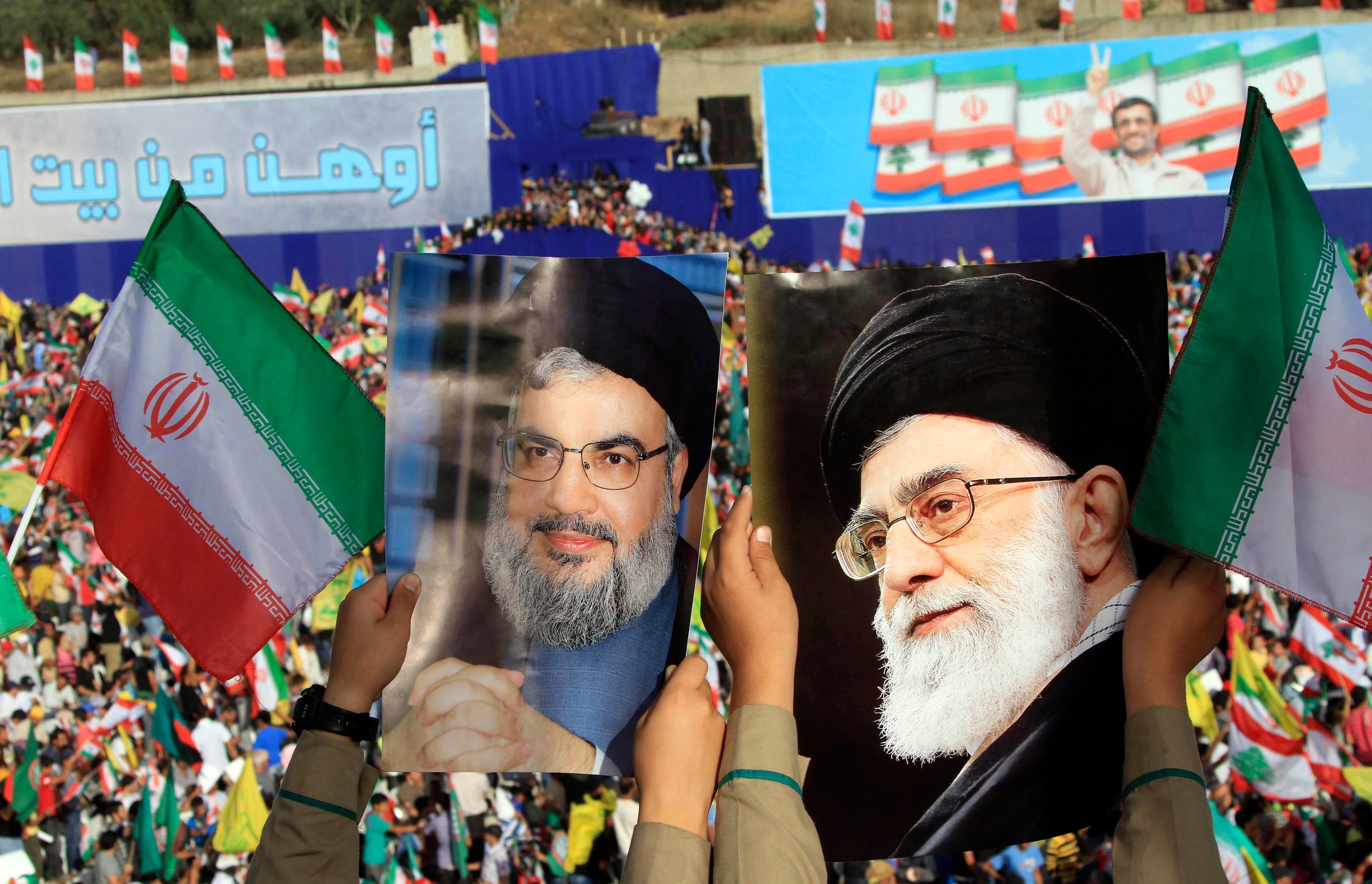 Two boys carry pictures of Hezbollah leader Hassan Nasrallah, left, and Iranian Supreme Leader Ali Khamenei, right, as thousands of Hezbollah supporters gather in a soccer field to listen to Iranian President Mahmoud Ahmadinejad 's speech during a rally in the southern town of Bint Jbeil, Lebanon on Oct. 14, 2010. (AP)