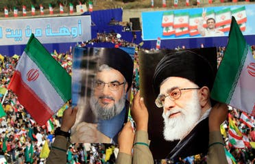Two boys carry pictures of Hezbollah leader Hassan Nasrallah, left, and Iranian Supreme Leader Ali Khamenei, right, as thousands of Hezbollah supporters gather in a soccer field to listen to Iranian President Mahmoud Ahmadinejad 's speech during a rally in the southern town of Bint Jbeil, Lebanon on Oct. 14, 2010. (AP)