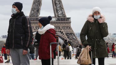 People walk near the Eiffel Tower wearing protective face masks amid the outbreak of COVID-19, the new coronavirus, on the Trocadero esplanade in Paris, on March 10, 2020.