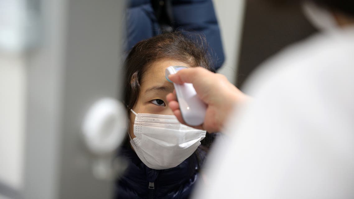 A child, wearing a protective face mask, following an outbreak of coronavirus, gets her temperature checked as she arrives at Stella Kids, daycare center in Tokyo, Japan, March 5, 2020. REUTERS/Stoyan Nenov