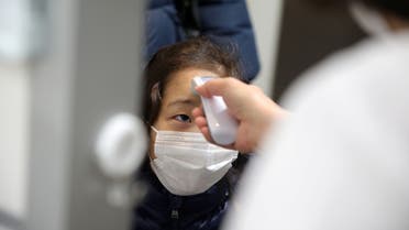 A child, wearing a protective face mask, following an outbreak of coronavirus, gets her temperature checked as she arrives at Stella Kids, daycare center in Tokyo, Japan, March 5, 2020. REUTERS/Stoyan Nenov