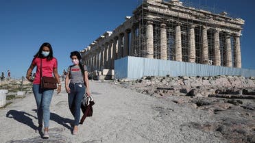 Visitors wear protective face masks as they walk past the ancient Parthenon temple at the archaeological site of the Acropolis in Athens. (Reuters)