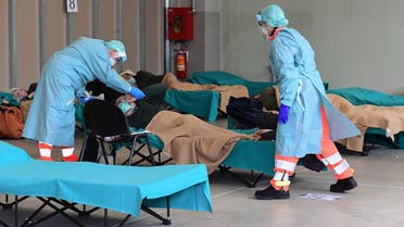 Hospital employees wearing a protection mask and gear tend to a patient (C) at a temporary emergency structure set up outside the accident and emergency department, where any new arrivals presenting suspect new coronavirus symptoms are being tested, at the Brescia hospital, Lombardy, on March 13, 2020. (AFP)