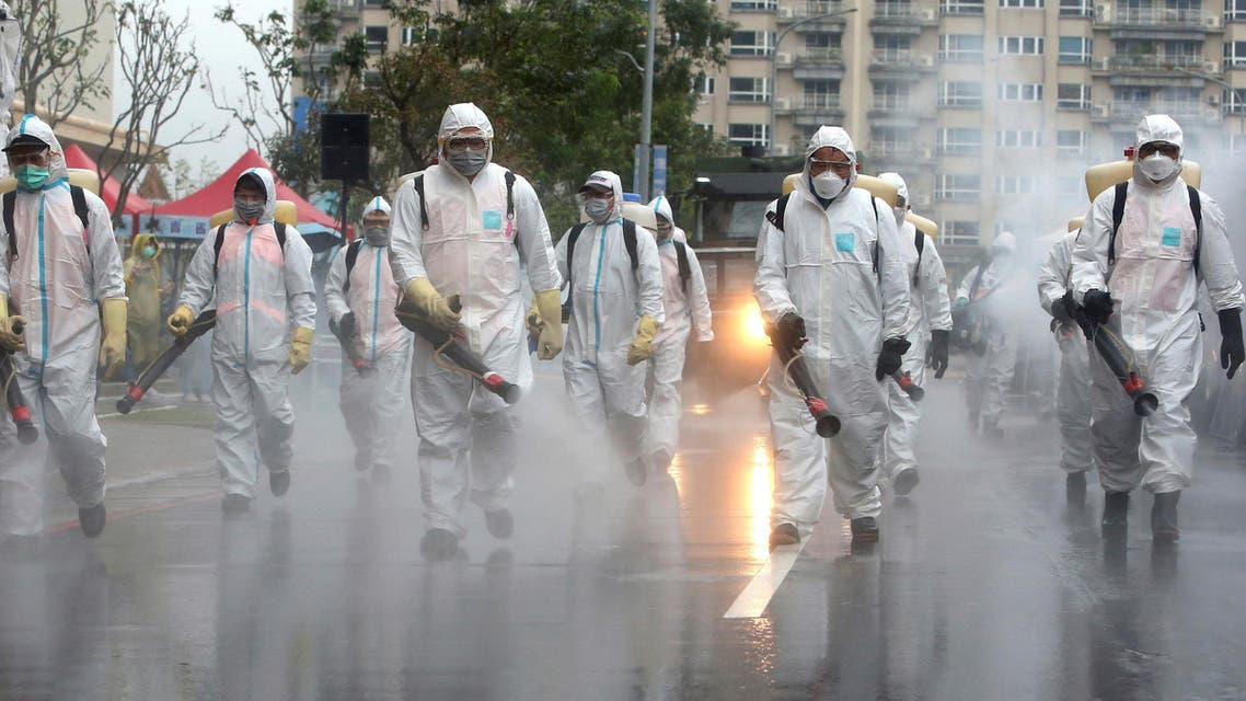 Taiwanese army soldiers wearing protective suits spray disinfectant over a road during a drill to prevent community cluster infection, in New Taipei City on March 14, 2020. (AP)