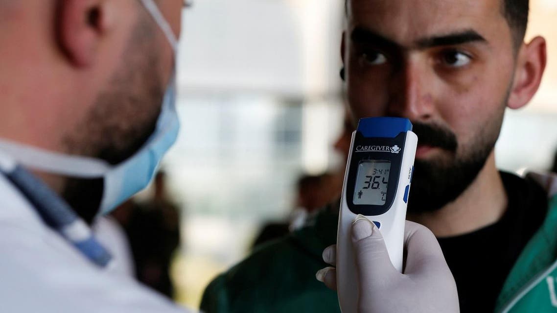 A medical staff member checks the temperature of a reporter during a media tour at the Queen Alia International Airport in Amman, Jordan March 4, 2020. (Reuters)
