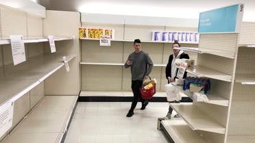 Shoppers walk through nearly empty shelves that usually hold toilet paper and paper towels, on Saturday, March 14, 2020, in a Target store in Olympia, Washington. (AP)