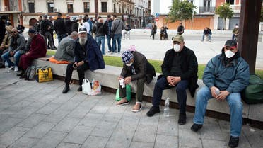 Moroccan nationals residing in countries such as France and Italy sit on a bench in the city of Algeciras on March 15, 2020, after being blocked from travel due to the lockdown measures. (AFP)