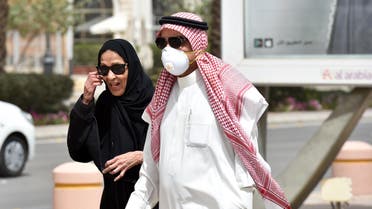 A Saudi man, wearing a protective mask as a precaution against coronavirus, walks with his wife along Tahlia street in the center of the capital Riyadh on March 15, 2020. (AFP)