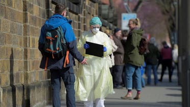 Medical staff inform people lining up for a test in a coronavirus disease (COVID-19) clearing-up centre in Dresden, Germany, March 16, 2020. (Reuters)