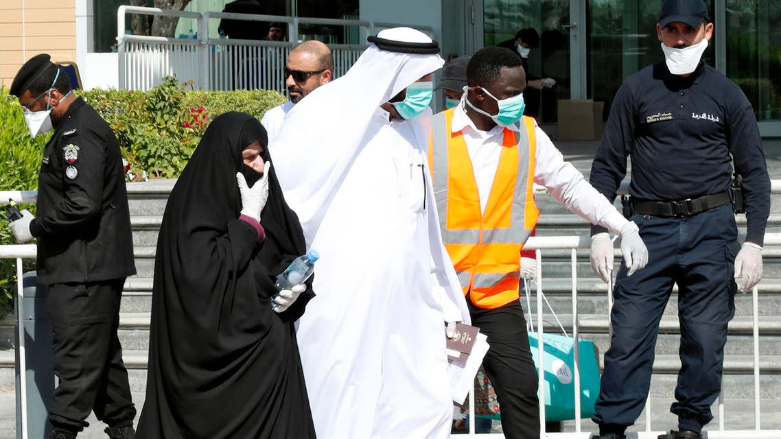 Qatari police stand outside a hotel in Doha as a medical worker walks alongside people wearing protective masks over fears of coronavirus, on March 12, 2020. (AFP)