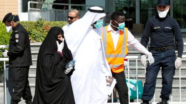 Qatari police stand outside a hotel in Doha as a medical worker walks alongside people wearing protective masks over fears of coronavirus, on March 12, 2020. (AFP)