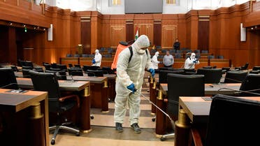 Workers wearing protective gear spray disinfectantat the main hall of the Lebanese Parliament, in Beirut on March 10, 2020. (AP)