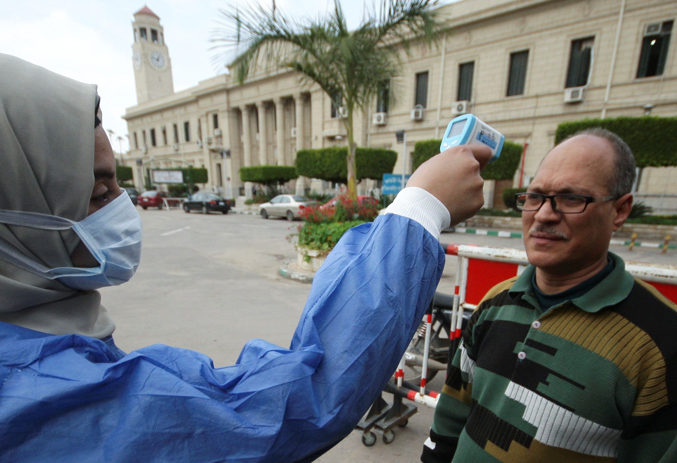إحدى العاملات بالرعاية الصحية تفحص حرارة شخص في جامعة القاهرة يوم 15 مارس