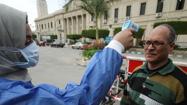 احدى العاملات بالرعاية الصحية تفحص حرارة شخص في جامعة القاهرة يوم 15 مارس