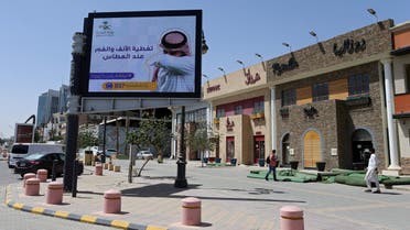 People walk near a banner with an instruction on personnel hygiene, following the outbreak of coronavirus, at a street in Riyadh, Saudi Arabia, March 16, 2020. The banner reads: "Wash hands with soap and water." (Reuters)
