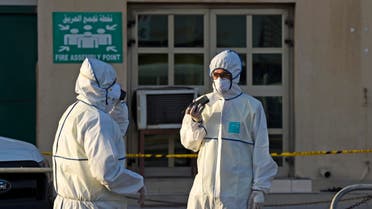 Bahraini policemen seal off a building housing foreign workers in the Salmabad industrial area as a precautionary measure after a resident tested positive for coronavirus (COVID-19), on the outskirts of the capital Manama on March 13, 2020. (AFP)