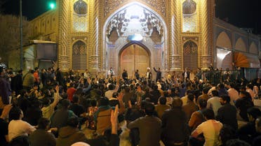 People gather outside the closed doors of the Fatima Masumeh shrine in Iran's holy city of Qom on March 16, 2020. (AFP)