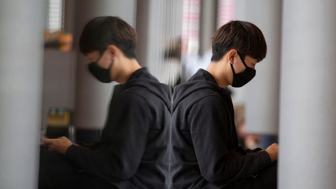 A man wearing a face mask checks his smartphone at Adolfo Suarez-Barajas international airport in Spain on March 17, 2020. (AP)