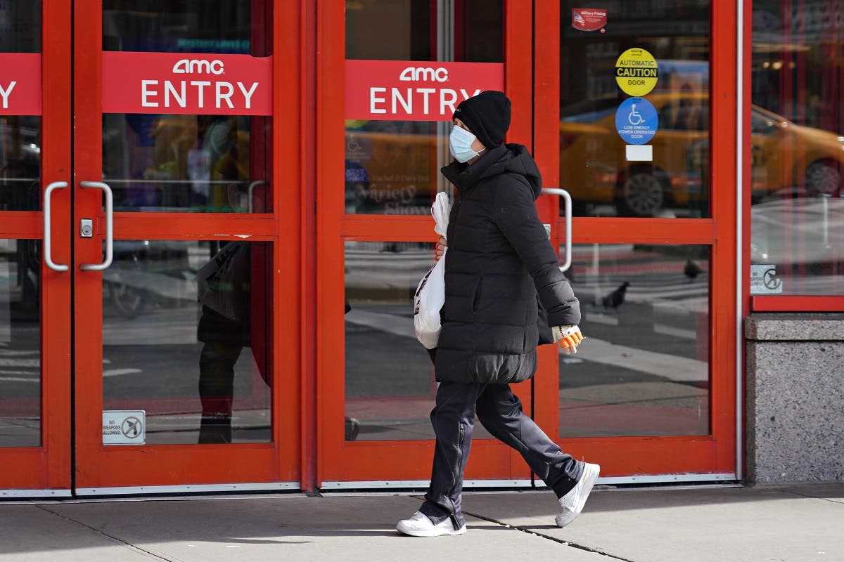 A person wears a protective mask while walking by an AMC movie theater as the coronavirus continues to spread across the United States on March 16, 2020 in New York City. (AFP)