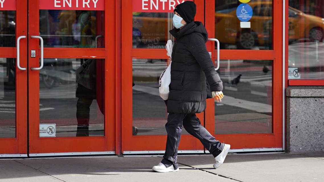A person wears a protective mask while walking by an AMC movie theater as the coronavirus continues to spread across the United States on March 16, 2020 in New York City. (AFP)