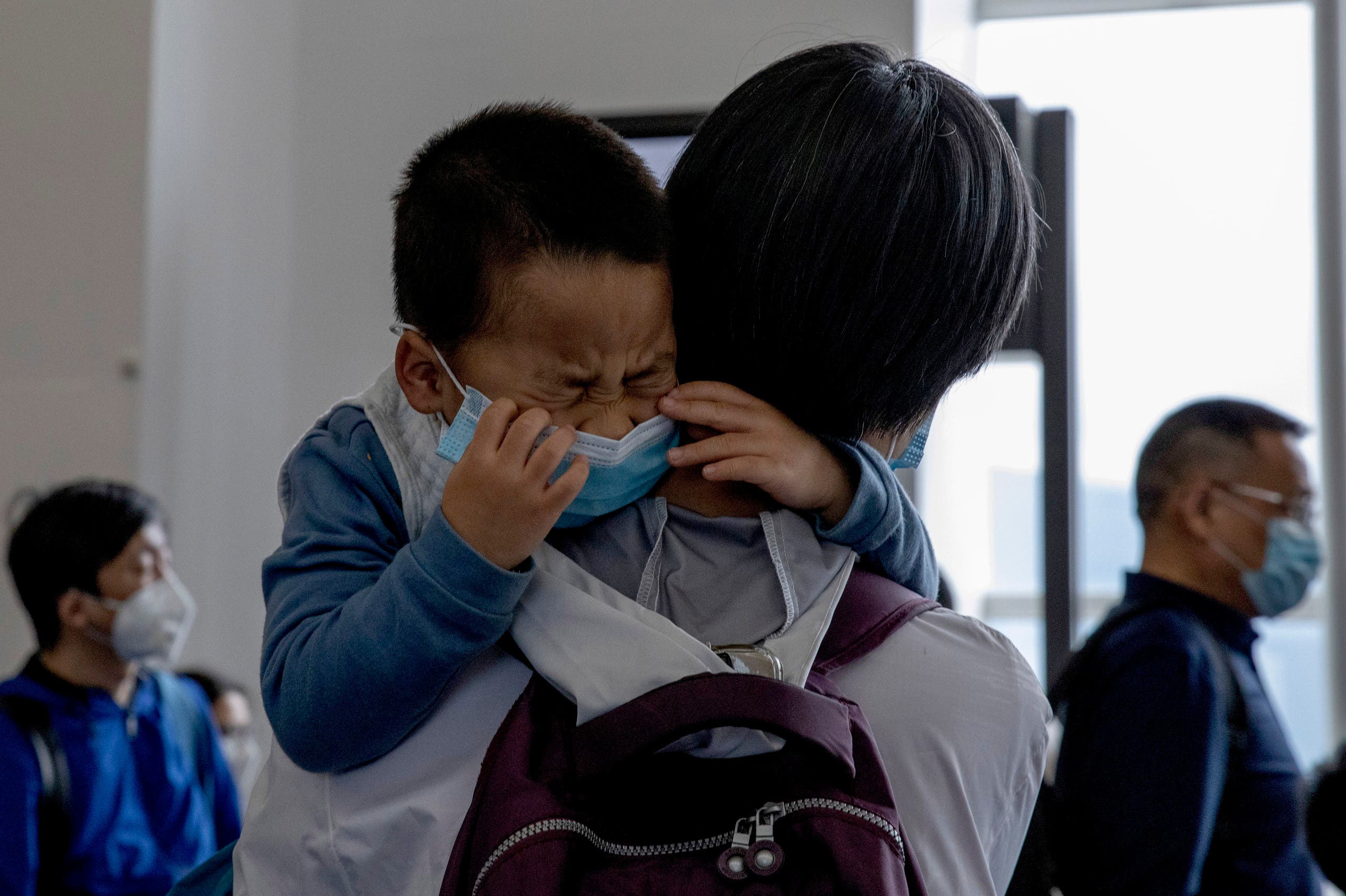 A child cries as he waits in line to board a plane for Beijing at the airport in Hong Kong on Feb. 9, 2020. (AP)