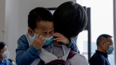 A child cries as he waits in line to board a plane for Beijing at the airport in Hong Kong on Feb. 9, 2020. (AP)