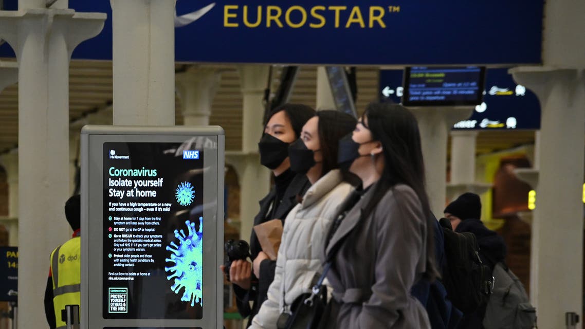 A notice warning people of the Coronavirus, is displayed as passengers wearing protective face masks pass through the Eurostar terminal at St Pancras International station in central London on March 17, 2020. The rail and maritime companies providing transport between France and Great Britain were adapting on Tuesday, March 17, to the new containment measures in France and to the closure to non-Europeans of the Schengen area. Eurostar, which runs high-speed trains between London and the mainland, canceled half of its trains on Tuesday.