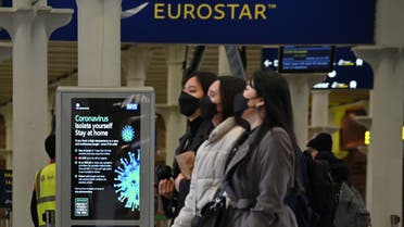 A notice warning people of the Coronavirus, is displayed as passengers wearing protective face masks pass through the Eurostar terminal at St Pancras International station in central London on March 17, 2020. The rail and maritime companies providing transport between France and Great Britain were adapting on Tuesday, March 17, to the new containment measures in France and to the closure to non-Europeans of the Schengen area. Eurostar, which runs high-speed trains between London and the mainland, canceled half of its trains on Tuesday.
