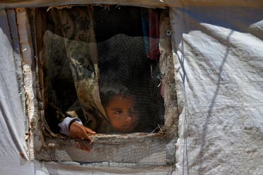 A Syrian refugee child looks through a window in his family tent in a refugee camp in the border town of Arsal, Lebanon, on June 16, 2019. (AP)