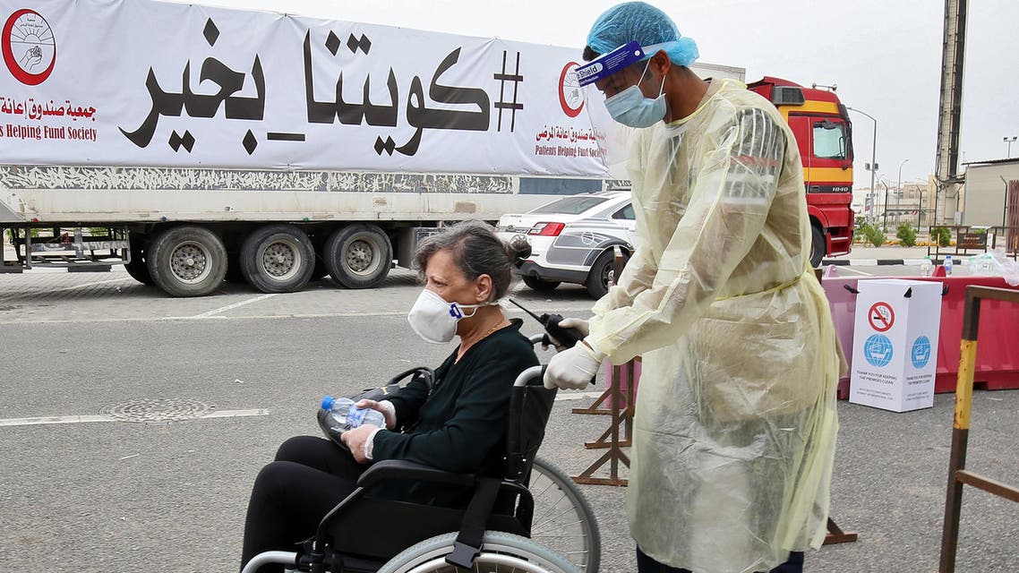 A woman is pushed on a wheelchair as she arrives at a Kuwaiti health ministry containment and screening zone for coronavirus disease for expatriates returning from Egypt, Syria, and Lebanon, in Kuwait City on March 15, 2020. (AFP)