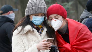 Ukrainians wearing face masks look at the latest news on a phone in Kyiv, Ukraine, Tuesday, March 17, 2020. (AP)