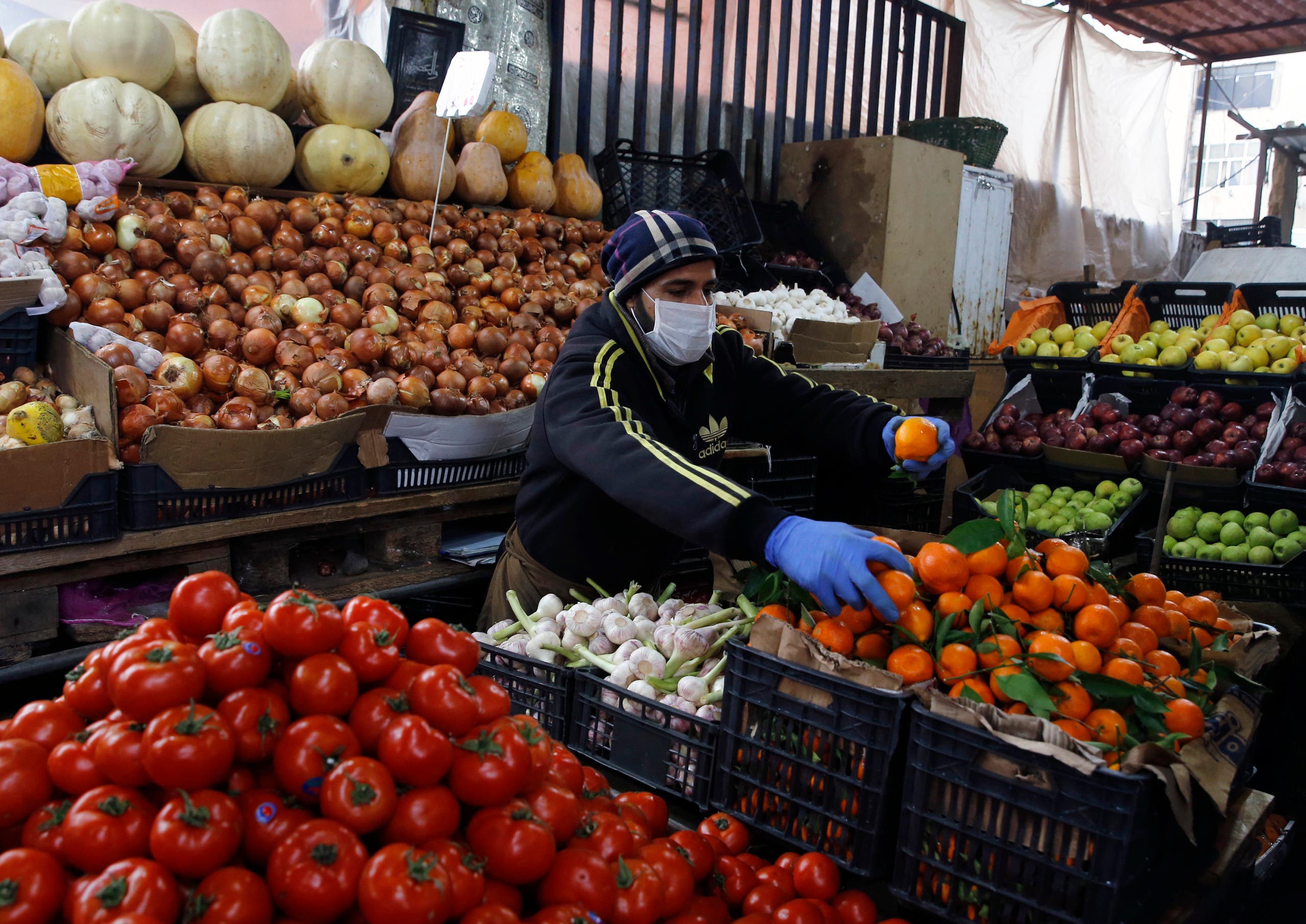Syrian Sami Jawabreh wears a mask and gloves, as he rearranges fruits on display for sale at his shop, in Beirut on March 18, 2020. (AP) 