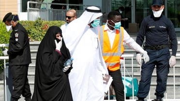 Qatari police stand outside a hotel in Doha as a medical worker walks alongside people wearing protective masks over fears of coronavirus, on March 12, 2020. (AFP)