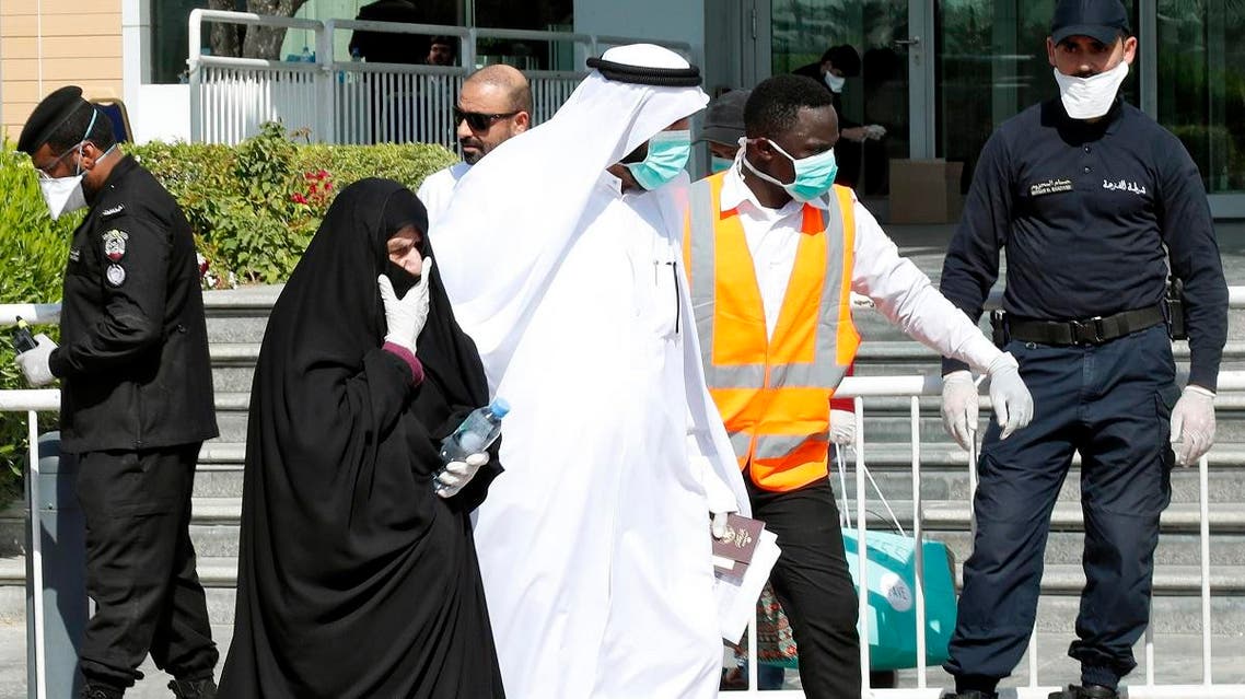 Qatari police stand outside a hotel in Doha as a medical worker walks alongside people wearing protective masks over fears of coronavirus, on March 12, 2020. (AFP)