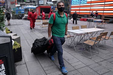 A man wearing a protective face mask walks with his luggage in Times Square, following the outbreak of Coronavirus disease (COVID-19), in the Manhattan borough of New York City, New York, US, March 19, 2020. (Reuters)