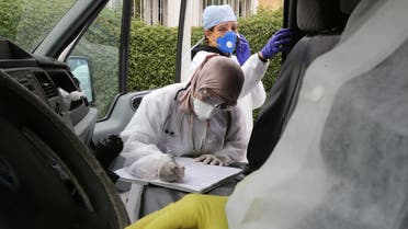 A member of the medical staff wearing a facial mask writes on file inside an ambulance at the hospital in Algiers, Algeria, on March 16, 2020. (Reuters)